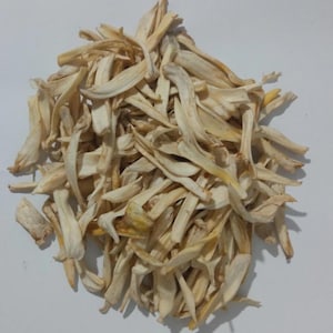May include: A pile of dried, light beige flower petals. The petals are long and slender, with a slightly curved shape. The overall appearance is dry and brittle, with some yellowing at the edges. The petals are arranged in a loose, overlapping pattern.
