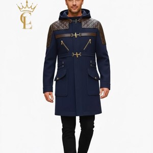 May include: A navy blue hooded coat with brown leather detailing on the shoulders and trim. The coat features gold-coloured clasps and pockets. The model is wearing black trousers and brown boots. The coat has a tailored fit.