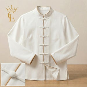 Può includere: Camicia bianca a maniche lunghe con colletto alla coreana e chiusure a frog. La camicia presenta finiture dorate sul colletto, sui polsini e sulla paramontura. Una piccola immagine mostra un primo piano della chiusura. Design classico e minimalista.