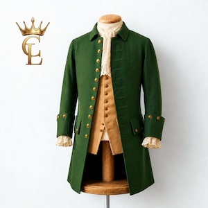 May include: A dark green long coat with gold-toned buttons, featuring a tan vest underneath and a white lace cravat at the neck. The coat has structured lapels, long sleeves with buttoned cuffs, and flap pockets on the front, displayed on a stand.
