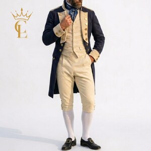 May include: A navy blue tailcoat jacket with gold buttons, worn over a beige waistcoat and matching beige knee-length breeches. The outfit includes a blue patterned cravat and white stockings, paired with black leather shoes featuring gold buckles.
