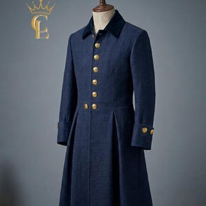 May include: A navy blue wool coat with a velvet collar and gold buttons. The long coat features a pleated skirt and buttoned cuffs. The coat is displayed on a mannequin. The coat's design is reminiscent of military or formal wear.