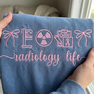 May include: A white ceramic mug with a black handle and the text "But First, Coffee" in a bold, black font. The mug is set against a blurred background, suggesting a cozy setting. The mug appears to be approximately 4 inches tall.