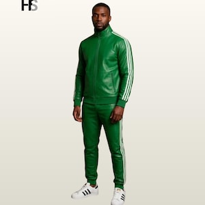 May include: A green leather tracksuit featuring a full-zip jacket with a high collar and matching slim-fit trousers. Both pieces are accented with three white stripes running down the sleeves and legs. The outfit is paired with white sneakers.