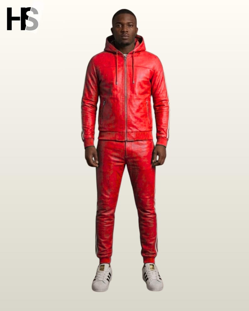 May include: A red leather tracksuit featuring a hooded zip-up jacket and matching trousers. Both pieces have white side stripes. The jacket includes a front zipper and drawstring hood. The trousers have a fitted cut. White sneakers complete the outfit.