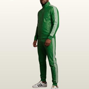 May include: A vibrant green leather tracksuit featuring a full-zip jacket with a high collar and matching slim-fit trousers. Both pieces are adorned with three white vertical stripes running down the sleeves and the outer legs. White sneakers.