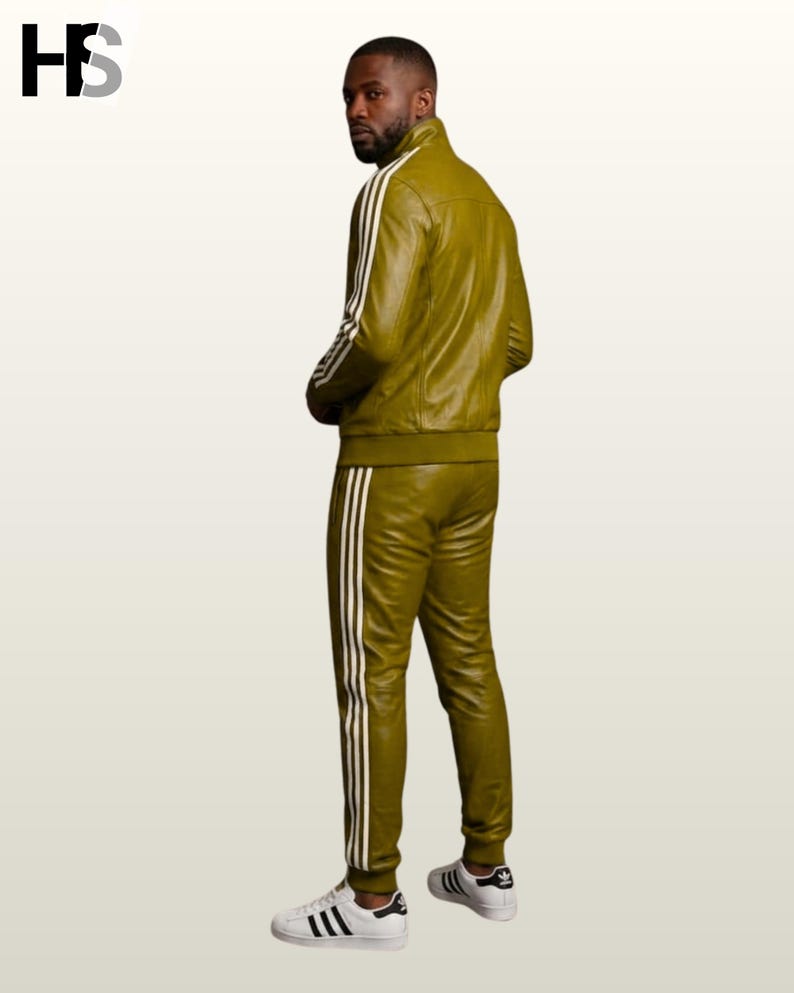 May include: An olive green leather tracksuit featuring a high-neck jacket and matching trousers, both adorned with three white vertical stripes along the sleeves and legs. The set is paired with white sneakers featuring black stripes and a logo.