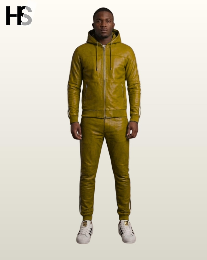 May include: An olive green leather tracksuit consisting of a zip-up hooded jacket with drawstrings and matching slim-fit joggers. Both pieces feature white side stripes along the arms and legs. The outfit is paired with white sneakers.