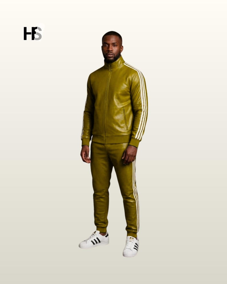 May include: An olive green track suit featuring a full-zip jacket with a high collar and matching slim-fit trousers. Both pieces are accented with three white vertical stripes along the sleeves and legs. The outfit is paired with white sneakers.