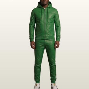 May include: A green leather tracksuit consisting of a hooded jacket with a full-length front zipper and matching slim-fit trousers. Both pieces feature white side stripes along the sleeves and legs. The outfit is paired with white sneakers.
