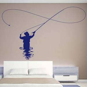 Puede incluir: Una silueta azul de una persona pescando con mosca en una pared sobre una cama blanca con una cabecera de color beige y una mesita de noche blanca.