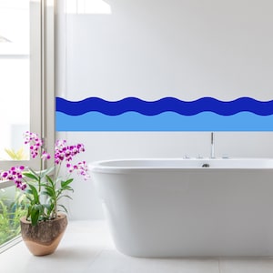 Puede incluir: Un baño moderno con una bañera blanca y un diseño de olas azules en la pared. Una orquídea en maceta con flores moradas cerca de una ventana añade un toque de color al espacio sereno.