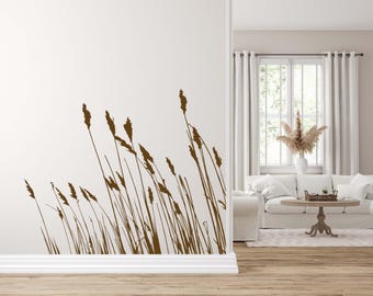 May include: A brown silhouette of tall grass blowing in the wind, against a white wall. The grass is in the lower right corner of the image. The wall is in the upper left corner of the image.