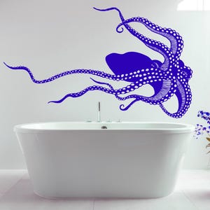 Könnte beinhalten: Ein blauer Tintenfisch-Wandaufkleber mit weißen Punkten, über einer weißen Badewanne in einem Badezimmer mit einer Pflanze in einem rosafarbenen Topf.
