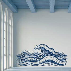 May include: A blue and white wall decal of a stylised ocean wave design. The wave is drawn in a vintage style with a large crest and smaller waves in the background.