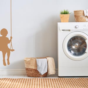 Child on swing wall decal rendered in a classic silhouette style, bringing a sense of innocence and the memory of carefree afternoons into the room.