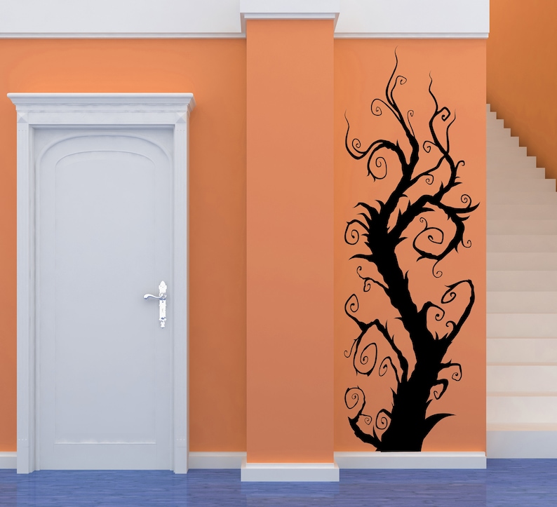 A tree with twisting branches and swirling vines on an orange wall. The tree is a wall decal.