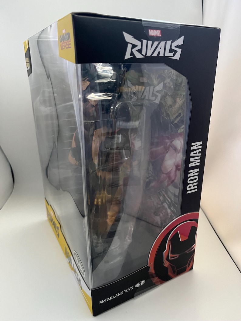 Może przedstawiać: Figurka akcji Iron Man z serii Marvel Rivals w oryginalnym opakowaniu. Czarne pudełko zawiera logo Marvel Rivals, napis Iron Man oraz grafikę hełmu postaci. Logo McFarlane Toys jest widoczne w dolnej części opakowania.