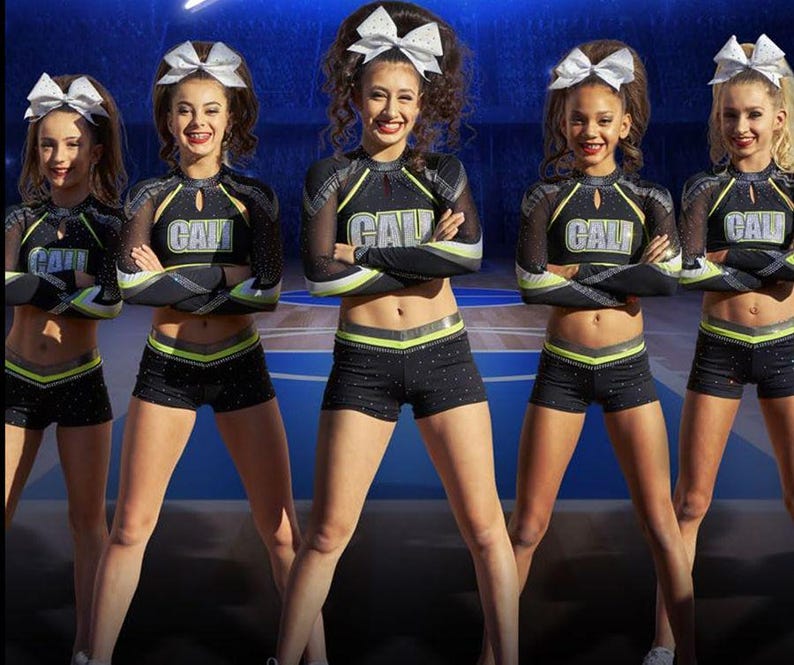 Puede incluir: Cinco animadoras con uniformes negros y verde ne&oacute;n a juego con la palabra "CAL" en la parte delantera. Llevan lazos blancos en el pelo y pantalones cortos negros. Los uniformes tienen mangas de malla y detalles en verde ne&oacute;n.