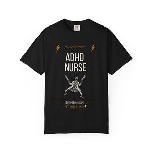 Op de afbeelding: Een zwart t-shirt met korte mouwen met de tekst NEURODIVERGENT, ADHD NURSE en Hyperfocused & Dangerous. De afbeelding bevat twee gele bliksemschichten en een skelet in een doktersjas dat twee grote injectiespuiten vasthoudt.