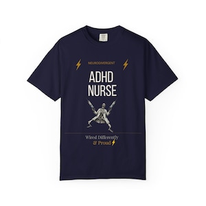 Può includere: Una t-shirt a maniche corte blu navy con la scritta bianca "NEURODIVERGENT ADHD NURSE" e due fulmini gialli. Sotto, uno scheletro in camice da laboratorio tiene due siringhe, con la scritta "Wired Differently & Proud" e un fulmine giallo.