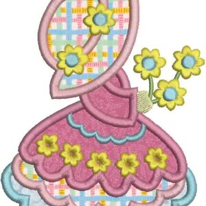 Pu&ograve; includere: Design ricamato di un cappello e di un vestito in rosa, blu e giallo. Il cappello ha un motivo a quadri al centro. Fiori gialli con centri blu sono posti sul cappello e sul vestito.