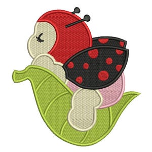 May include: An embroidered design of a ladybug with a red head and black wings with red spots. The ladybug is resting on a green leaf with a white and pink background. The design is suitable for embroidery projects.