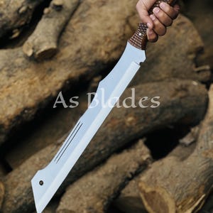 May include: A large, silver blade with a wooden handle. The blade has a unique shape with a pointed tip and a series of parallel lines etched near the center. The handle is intricately carved with a textured pattern. The text "As Blades" is visible.