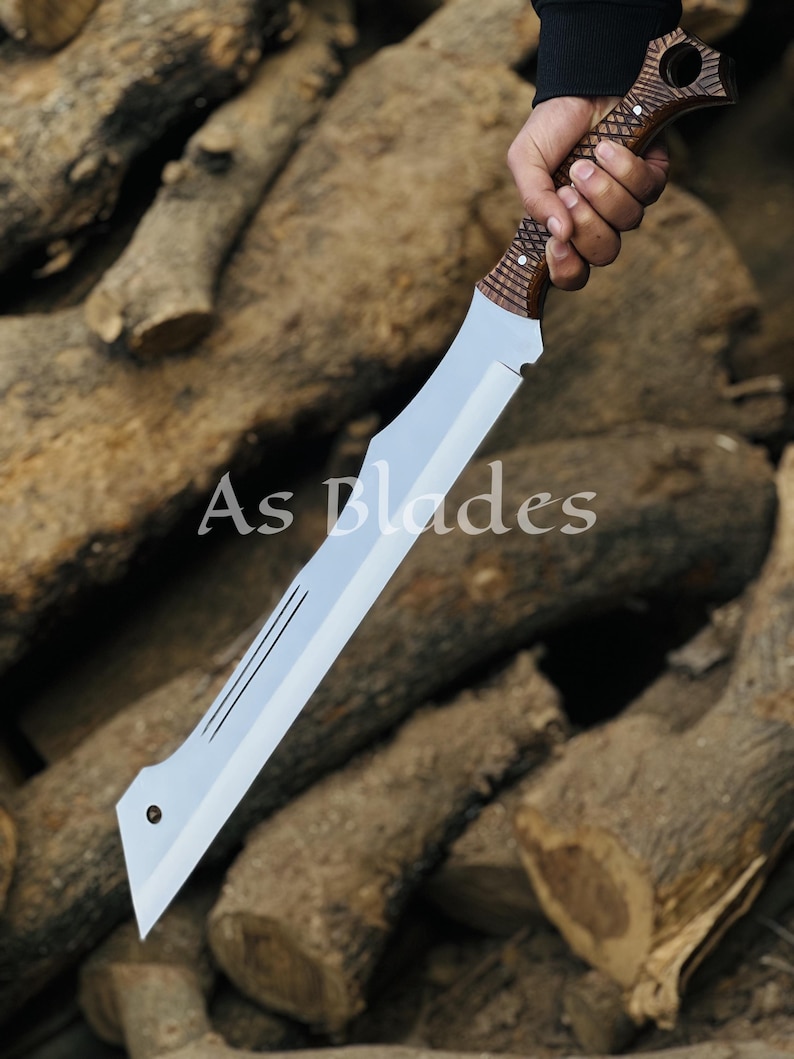 May include: A large, silver blade with a wooden handle. The blade has a unique shape with a pointed tip and a series of parallel lines etched near the center. The handle is intricately carved with a textured pattern. The text "As Blades" is visible.