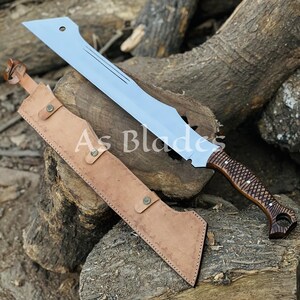 May include: A large, silver-colored blade with a brown wooden handle and a leather sheath. The blade has a unique shape with a curved edge and a series of grooves. The handle is intricately carved. The sheath is tan and has a button closure. The text "As Blades" is visible.