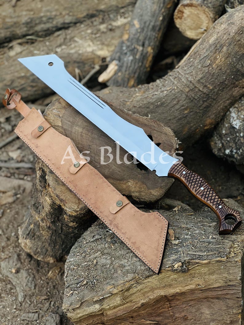 May include: A large, silver-colored blade with a brown wooden handle and a leather sheath. The blade has a unique shape with a curved edge and a series of grooves. The handle is intricately carved. The sheath is tan and has a button closure. The text "As Blades" is visible.