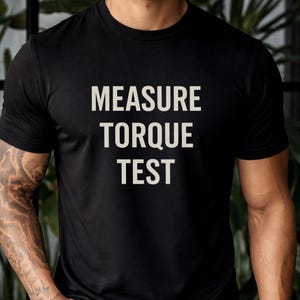 Peut inclure: T-shirt noir à col rond avec l'inscription "MEASURE TORQUE TEST" imprimée en blanc. Le t-shirt est fait d'une matière douce et convient aux tenues décontractées. Le texte est centré sur la poitrine.