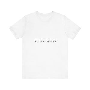 May include: A white short-sleeved t-shirt featuring the text HELL YEAH BROTHER printed in black capital letters across the centre of the chest. The garment has a crew neckline and a standard fit, presented against a plain white background.
