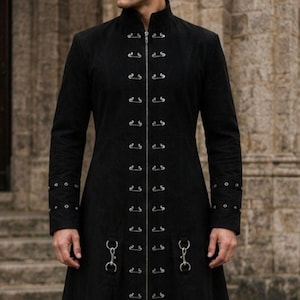 May include: A long black coat with a high collar and decorative metal clasps. The coat features long sleeves and a flared skirt, creating a dramatic silhouette. The coat is made of a dark material, possibly suede-like. The coat's length is approximately 150 cm.