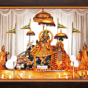 May include: A framed religious artwork featuring two ornate figures adorned in gold and orange garments, set against a backdrop of white curtains. The scene includes decorative flags, umbrellas, and a golden altar, creating a detailed and vibrant composition.