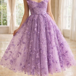Puede incluir: Un vestido formal de color lavanda con adornos florales. El vestido presenta un corpi&ntilde;o ajustado, una cintura ce&ntilde;ida y una falda fluida hasta la rodilla. Los hombros est&aacute;n adornados con detalles florales, y el vestido se combina con tacones de tonos neutros.