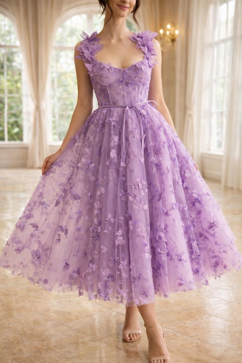 Puede incluir: Un vestido formal de color lavanda con adornos florales. El vestido presenta un corpi&ntilde;o ajustado, una cintura ce&ntilde;ida y una falda fluida hasta la rodilla. Los hombros est&aacute;n adornados con detalles florales, y el vestido se combina con tacones de tonos neutros.