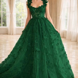 Puede incluir: Vestido largo esmeralda con aplicaciones florales. El vestido presenta un escote coraz&oacute;n, un corpi&ntilde;o ajustado y una falda fluida. Los hombros est&aacute;n adornados con adornos florales y un cintur&oacute;n de cinta ci&ntilde;e la cintura. Adecuado para eventos formales.