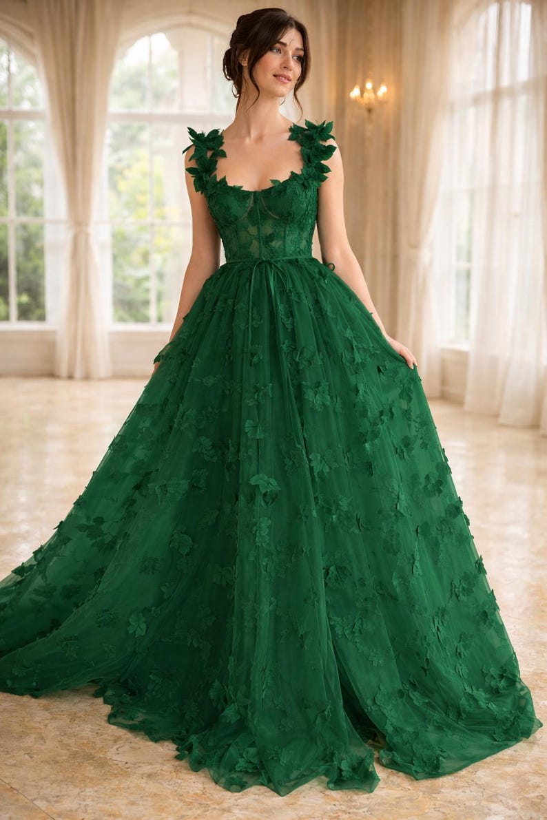 Puede incluir: Vestido largo esmeralda con aplicaciones florales. El vestido presenta un escote coraz&oacute;n, un corpi&ntilde;o ajustado y una falda fluida. Los hombros est&aacute;n adornados con adornos florales y un cintur&oacute;n de cinta ci&ntilde;e la cintura. Adecuado para eventos formales.