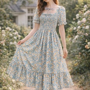 Puede incluir: Vestido azul claro con estampado floral, escote cuadrado y mangas cortas. El vestido presenta un corpiño ajustado y una falda fluida con dobladillo con volantes. El vestido está adornado con un estampado de margaritas.