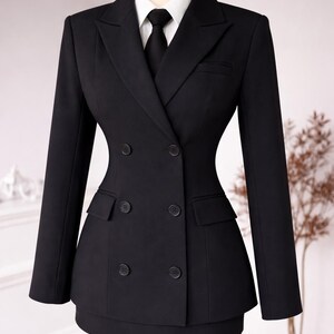 May include: A black double-breasted suit with a white collared shirt and black tie. The suit features a tailored fit with a skirt, and is displayed on a mannequin. The suit has two rows of buttons and two front pockets.