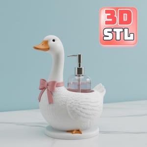 May include: A white goose-shaped soap dispenser with a pink bow tie and orange beak. The dispenser holds a clear bottle with a silver pump. The base is white, and the background is a light blue.