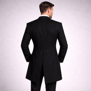 May include: A black formal tailcoat with a notched lapel and a split back. The coat has a fitted silhouette and is worn over a white collared shirt. The back of the coat features two buttons and a long, elegant tail.