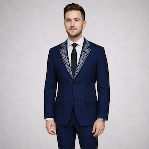 May include: A navy blue pinstripe suit with ornate silver embroidery on the lapels. The suit includes a matching jacket and trousers, a white dress shirt, and a black tie. The ensemble is a formal outfit.