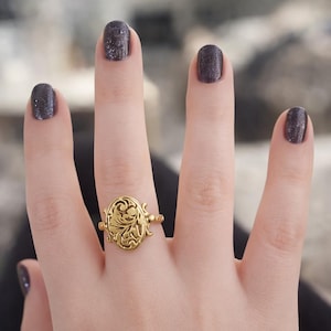 Anillo de veneno de estilo victoriano: medallón ovalado de oro con compartimento oculto. Joyería llamativa de inspiración antigua.