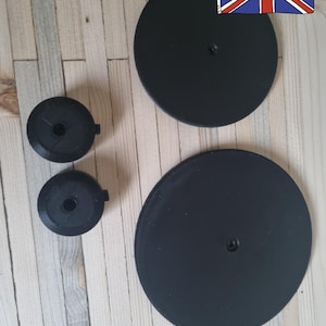 May include: Several black circular objects and smaller black circular objects are arranged on a light wood-grain surface. The text "Made in the UK" is visible in red, with a Union Jack flag illustration.