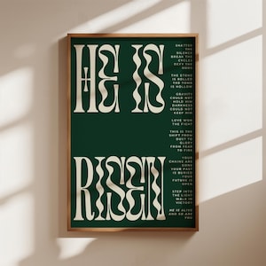 Könnte beinhalten: Ein gerahmter Kunstdruck mit den Worten "He Is Risen" in großen, stilisierten weißen Buchstaben auf einem dunkelgrünen Hintergrund. Der Druck enthält zusätzlichen Text mit inspirierenden Sätzen. Der Rahmen hat eine warme braune Farbe.