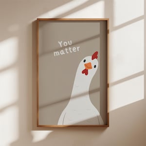 Könnte beinhalten: Gerahmter Kunstdruck mit einer Cartoon-Hühner-Illustration. Das Huhn hat einen roten Kamm und einen orangefarbenen Schnabel. Der Text "You matter" steht über dem Huhn. Der Druck ist in Holz gerahmt.