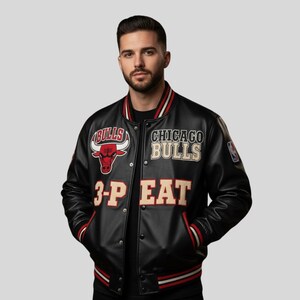 Puede incluir: Chaqueta universitaria negra de los Chicago Bulls con detalles rojos y blancos. La chaqueta presenta el logotipo del equipo, las palabras "CHICAGO BULLS" y "3-PEAT". Tiene cierre de botones y bolsillos.