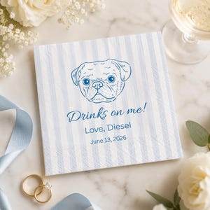 Może przedstawiać: Kwadratowa papierowa serwetka z niebiesko-białymi pionowymi paskami. U góry znajduje się niebieski rysunek twarzy mopsa. Tekst "Drinks on me! Love, Diesel June 13, 2026" jest wydrukowany na niebiesko. Złote pierścionki i kieliszek wina w tle.